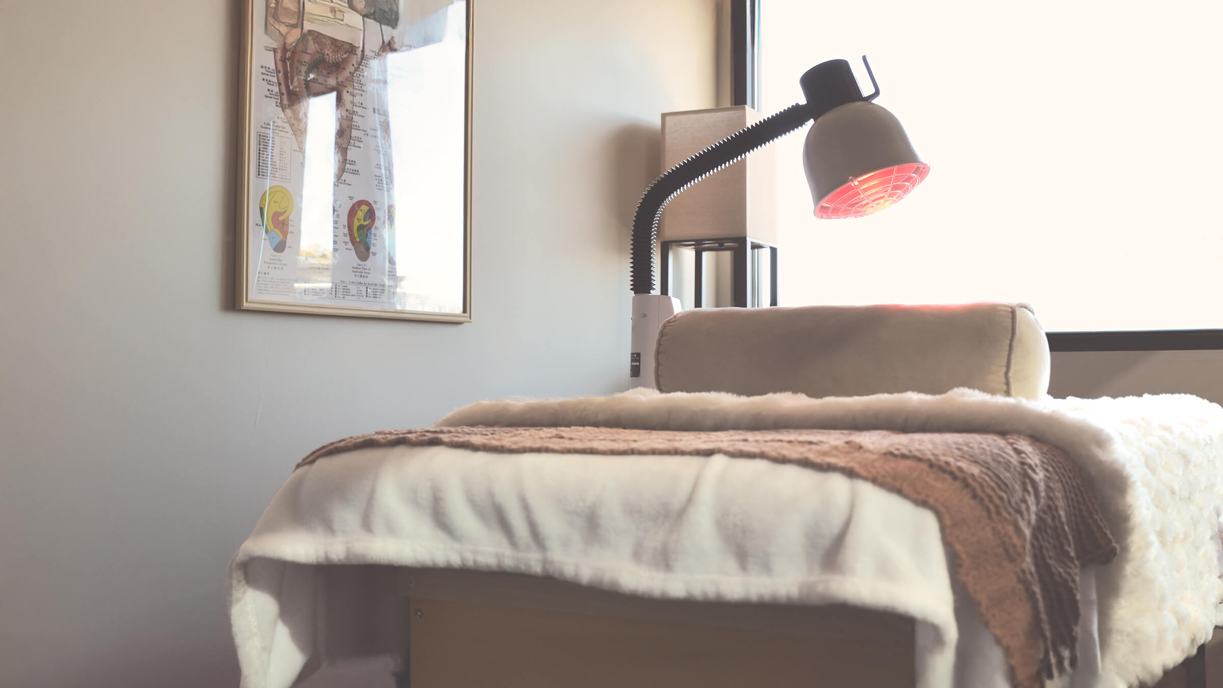 Treatment room at Castle Rock Wellness with red light therapy lamp and cozy treatment bed.