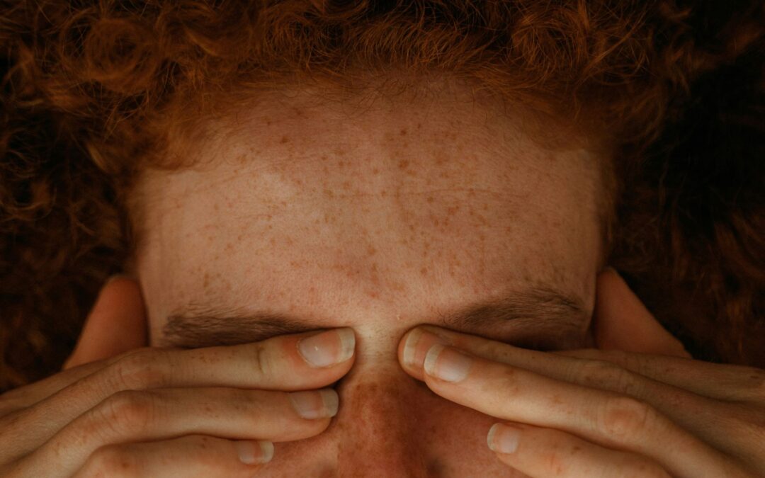 Woman pressing her fingers to her eyes as she tries to find relief from a migraine headache.